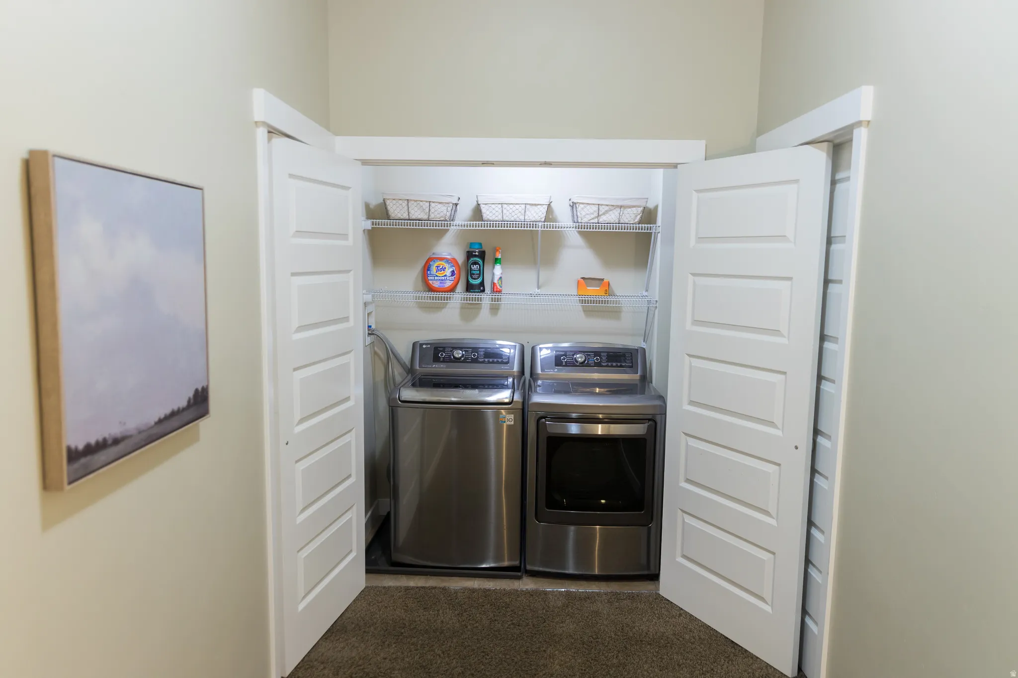 Laundry closet featuring a washer and dryer, built-in shelving, and bifold doors
