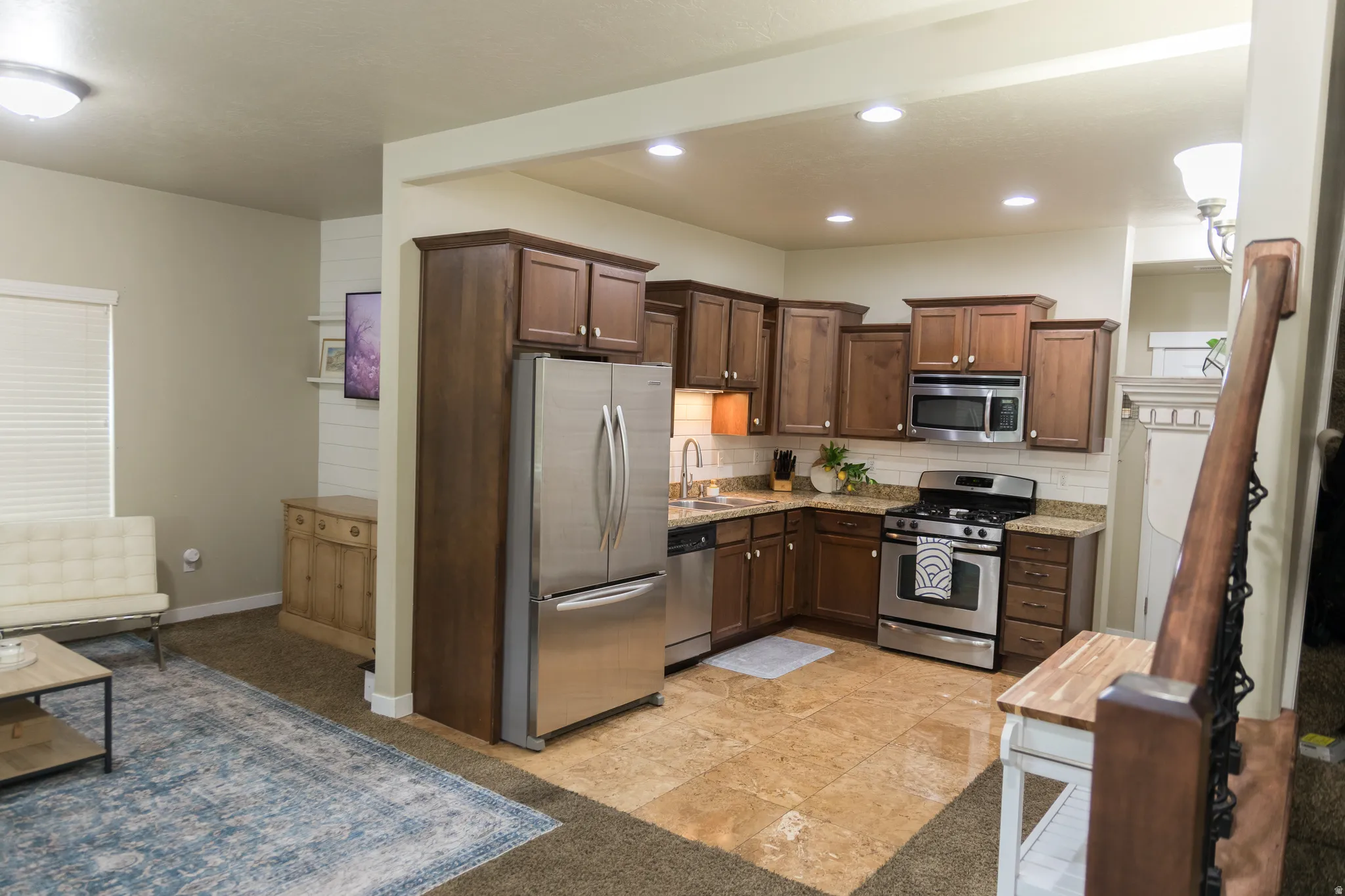 Kitchen featuring wood-finish cabinetry, stainless steel appliances, tile flooring, and a subway tile backsplash
