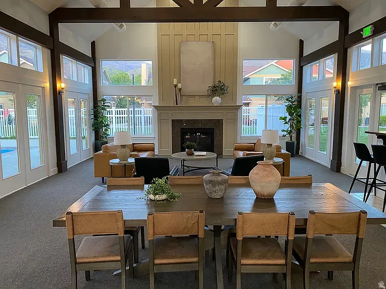 Vaulted ceiling with exposed wood beams, built-in fireplace with mantel, multiple French doors, large windows, and carpet flooring
