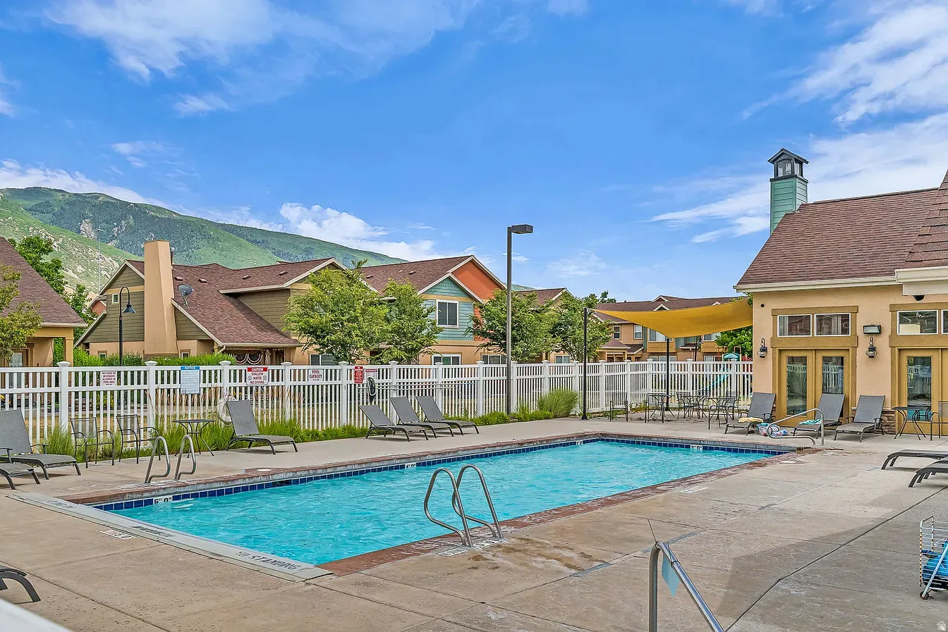 Outdoor swimming pool with concrete surround, perimeter fencing, and an adjacent building featuring multiple glass-paned doors