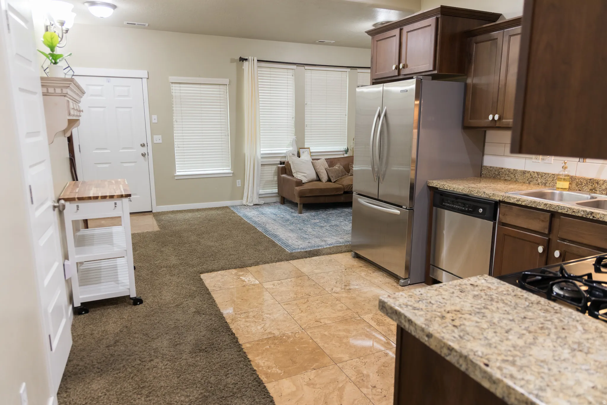 Kitchen featuring granite-style countertops, dark wood cabinetry, and stainless steel appliances