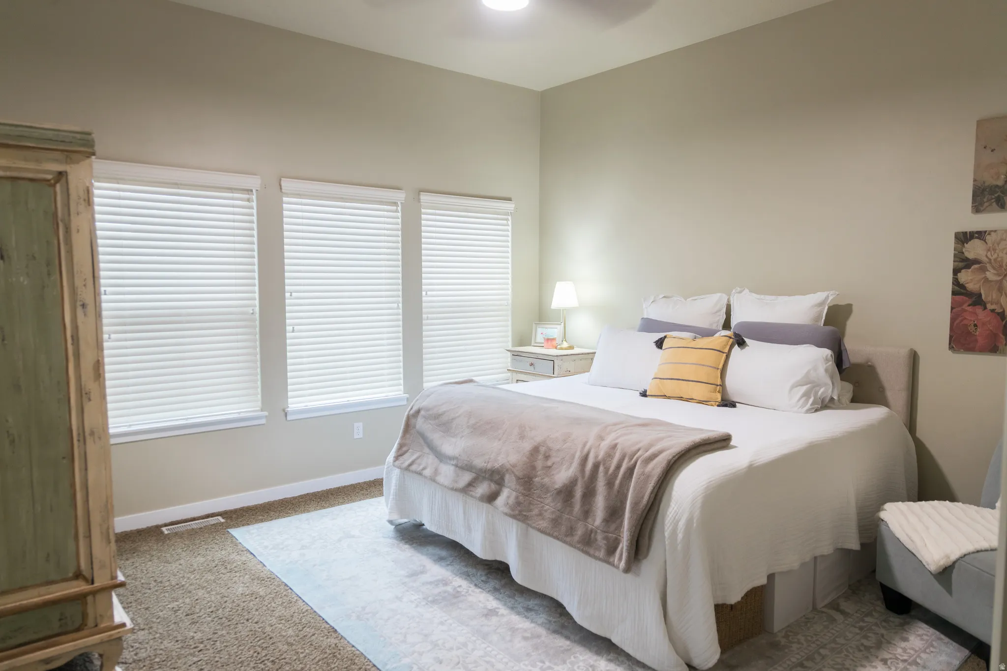 Recessed ceiling lighting, three windows with blinds, carpeted flooring, and neutral wall tones