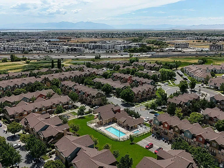 Multiple residential buildings with varied facade colors, brown shingle roofing, and established landscaping