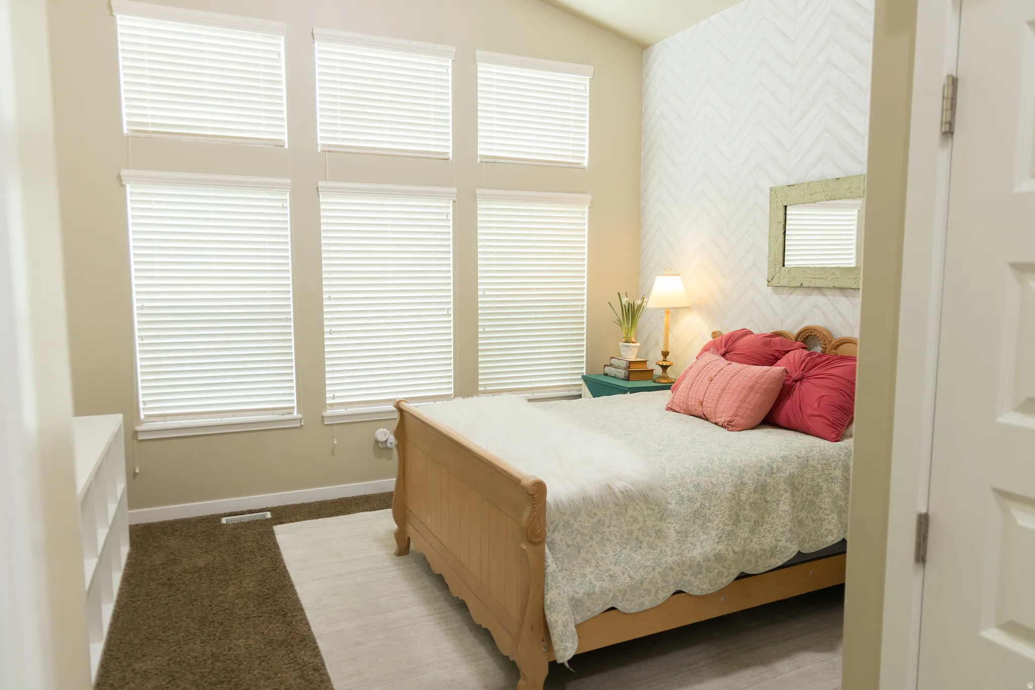 Vaulted ceiling with multiple windows, accent wall with geometric pattern, wood finish flooring, and built-in shelving