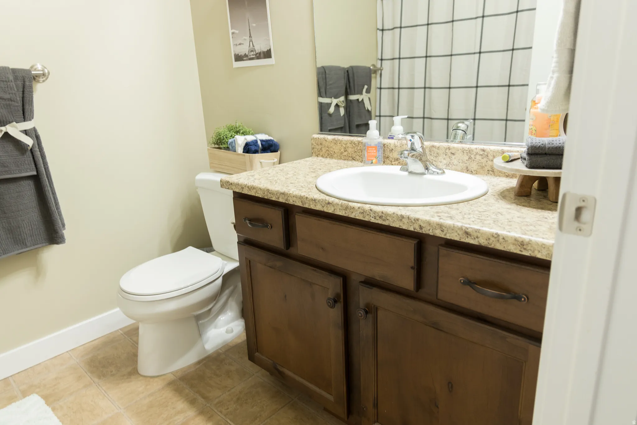 Vanity with an integrated sink, granite-patterned countertop, and wood-finish cabinetry