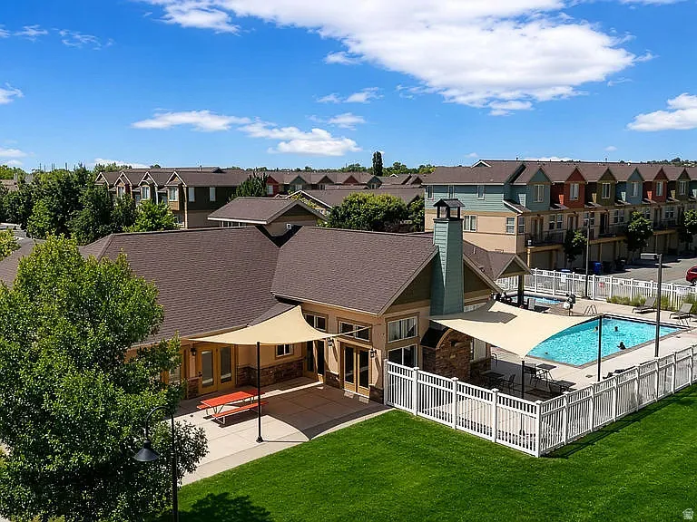 Community clubhouse featuring a swimming pool, concrete patio, and shade sails