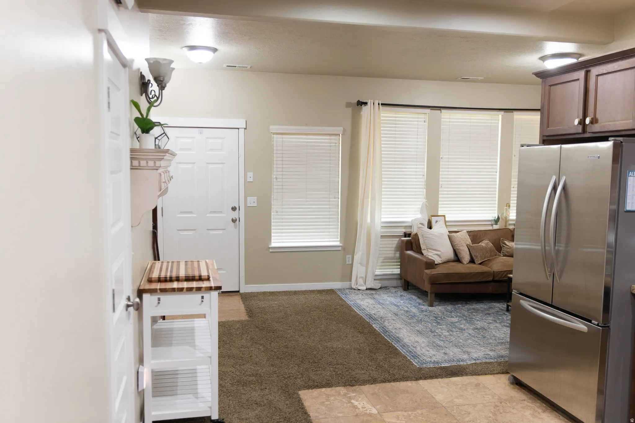 Neutral wall finishes, recessed lighting, and a stainless steel refrigerator