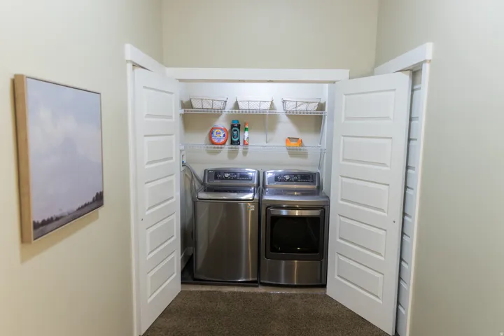 Laundry closet featuring a washer and dryer, built-in shelving, and bifold doors