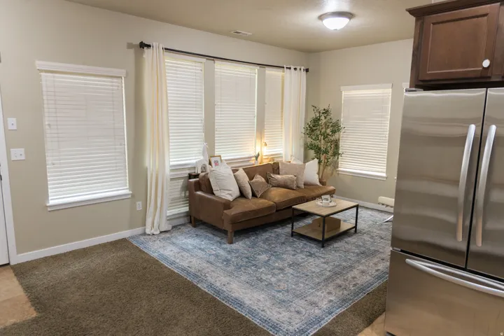 Recessed lighting, multiple windows with blinds, built-in upper cabinetry, and stainless steel refrigerator