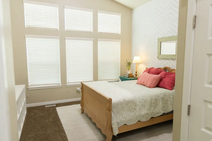 Vaulted ceiling with multiple windows, accent wall with geometric pattern, wood finish flooring, and built-in shelving