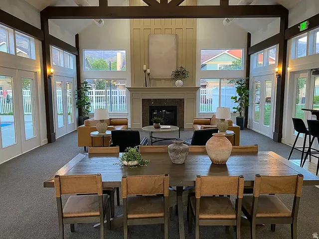 Vaulted ceiling with exposed wood beams, built-in fireplace with mantel, multiple French doors, large windows, and carpet flooring
