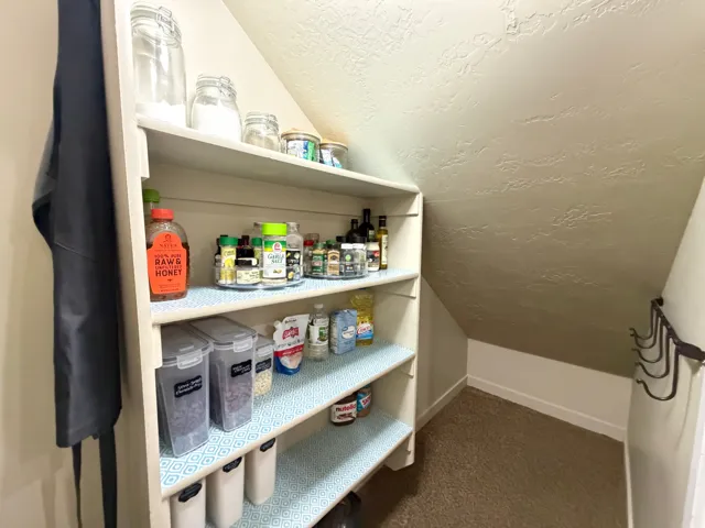 Built-in shelving with multiple levels, textured ceiling, and wall-mounted storage hooks