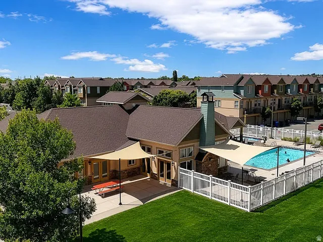 Community clubhouse featuring a swimming pool, concrete patio, and shade sails