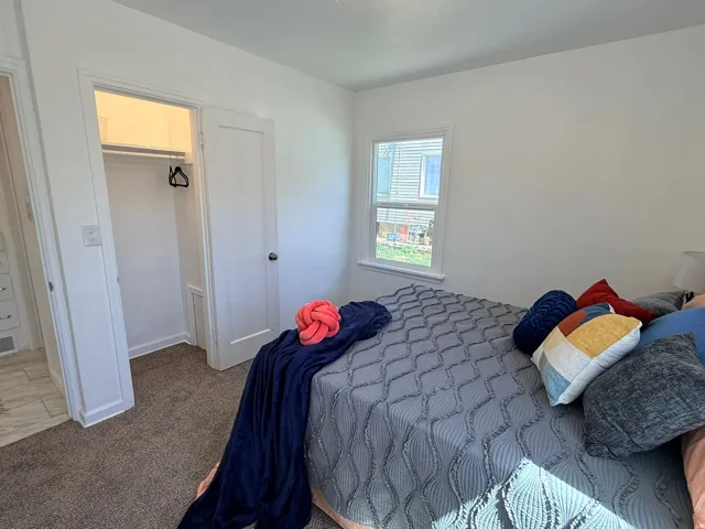 Carpeted flooring, white walls, and a window with white trim