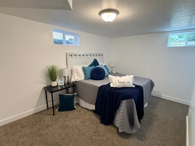 Carpeted room featuring a white paneled headboard, recessed window, and flush-mount ceiling light