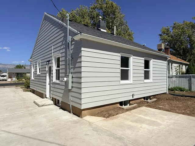 Light gray siding exterior with white window trim and a dark shingle roof