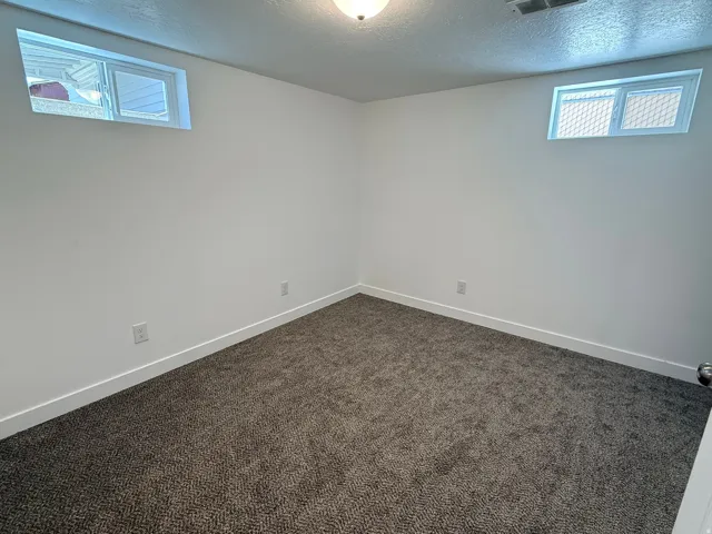 Freshly painted white walls, dark gray patterned carpeting, recessed ceiling light, and two transom windows