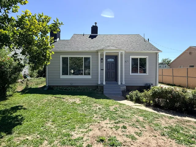 Light gray exterior siding, white trim windows, front entry with white columns, dark gray front door, and a gray shingle roof