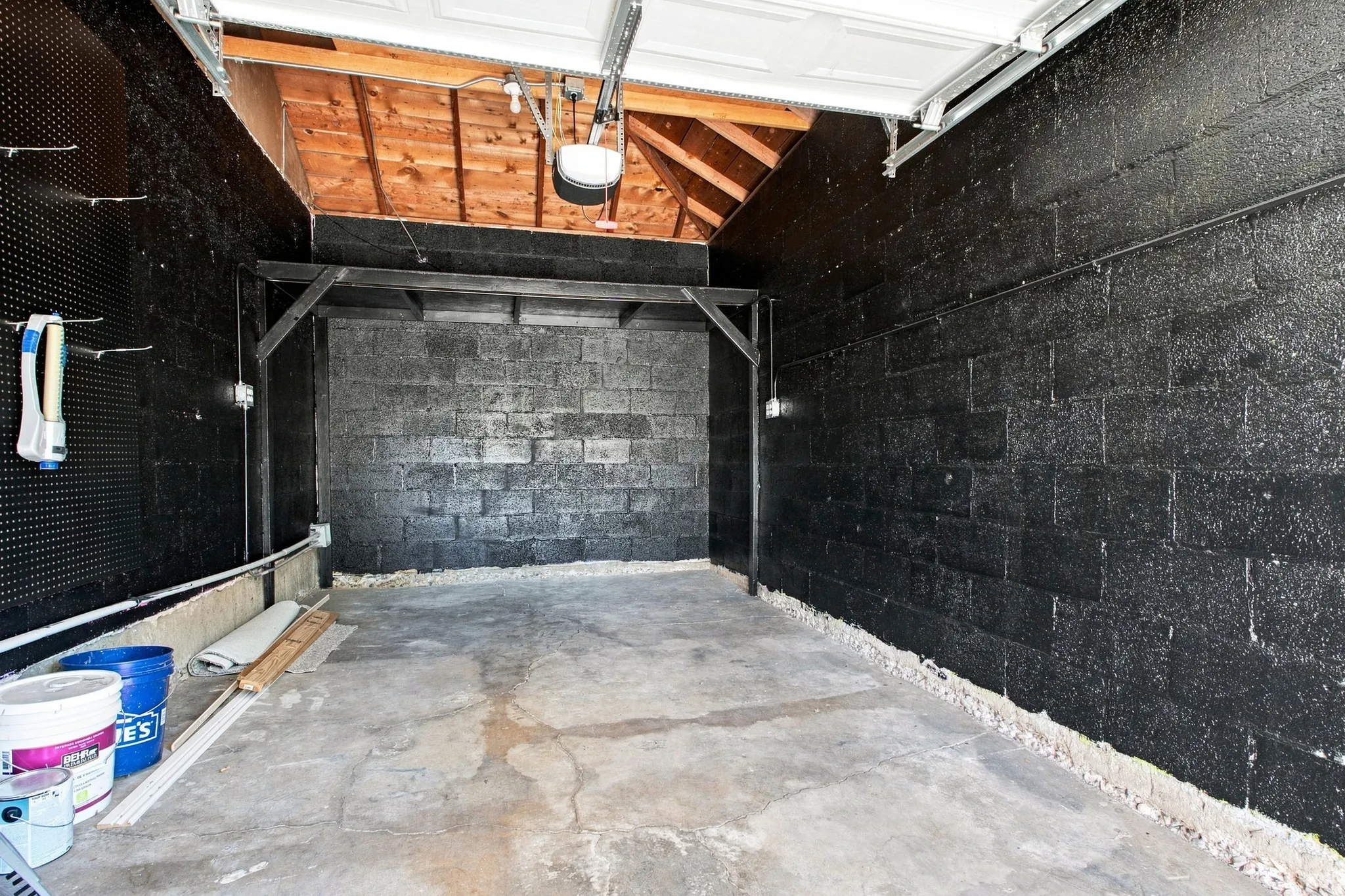 Exposed wood beam ceiling, concrete block walls, and concrete flooring