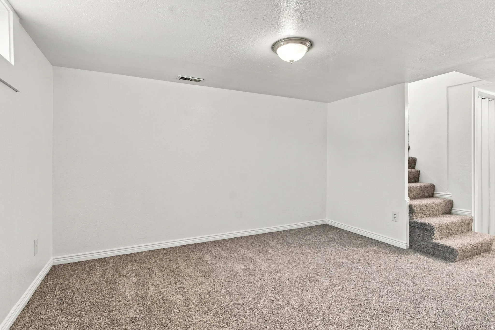 Recessed window, ceiling-mounted light fixture, carpeted flooring, and a carpeted staircase