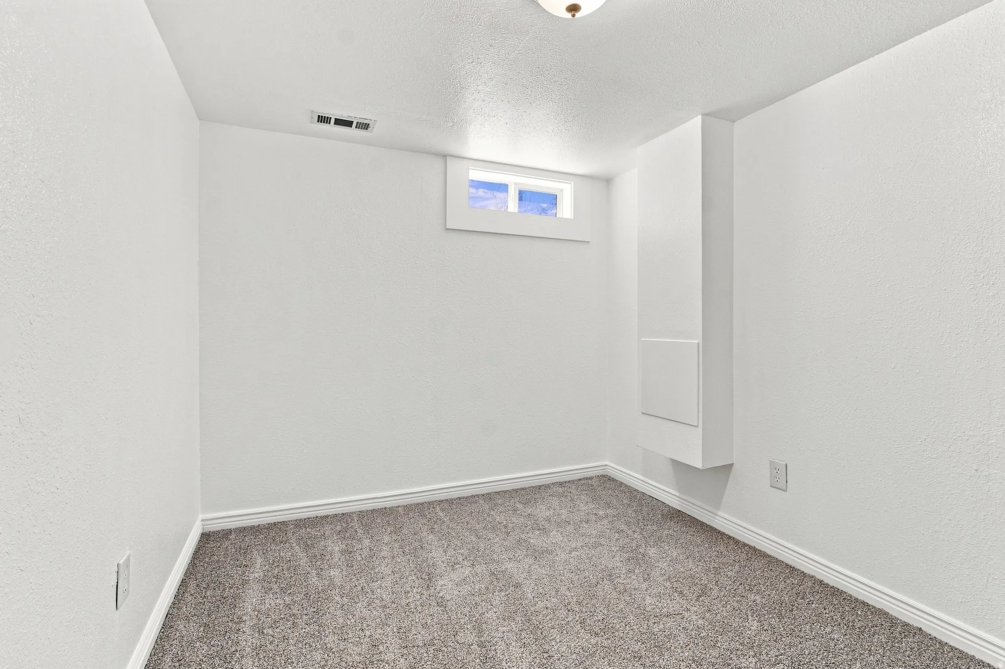 Neutral-toned carpeting, white painted walls, and a recessed window