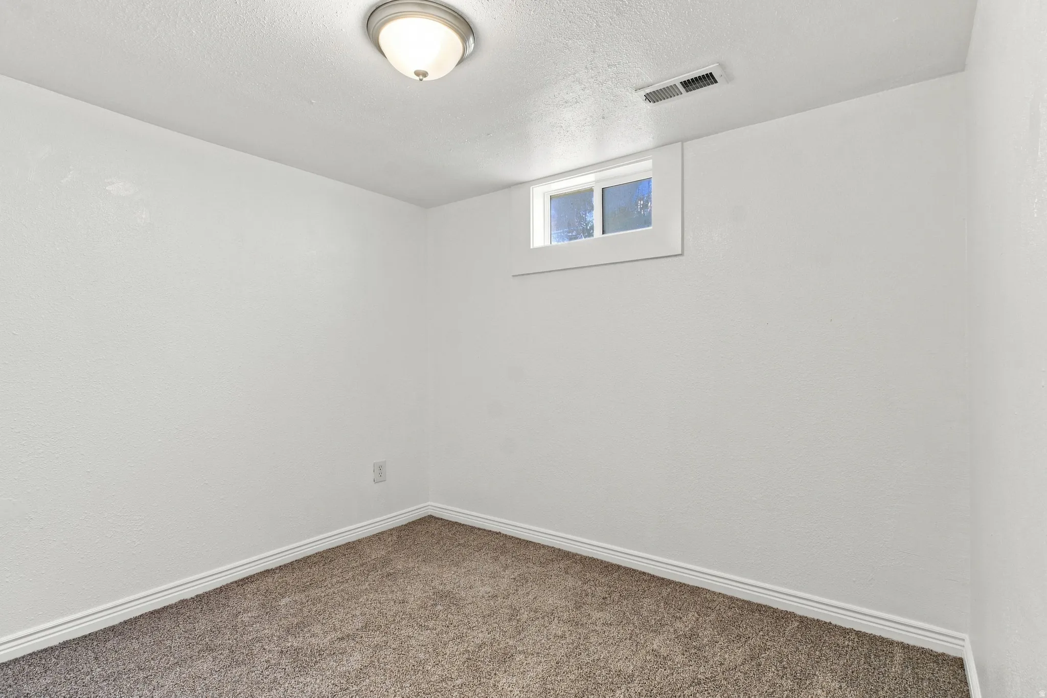 Neutral wall finish, ceiling-mounted light fixture, and a single window
