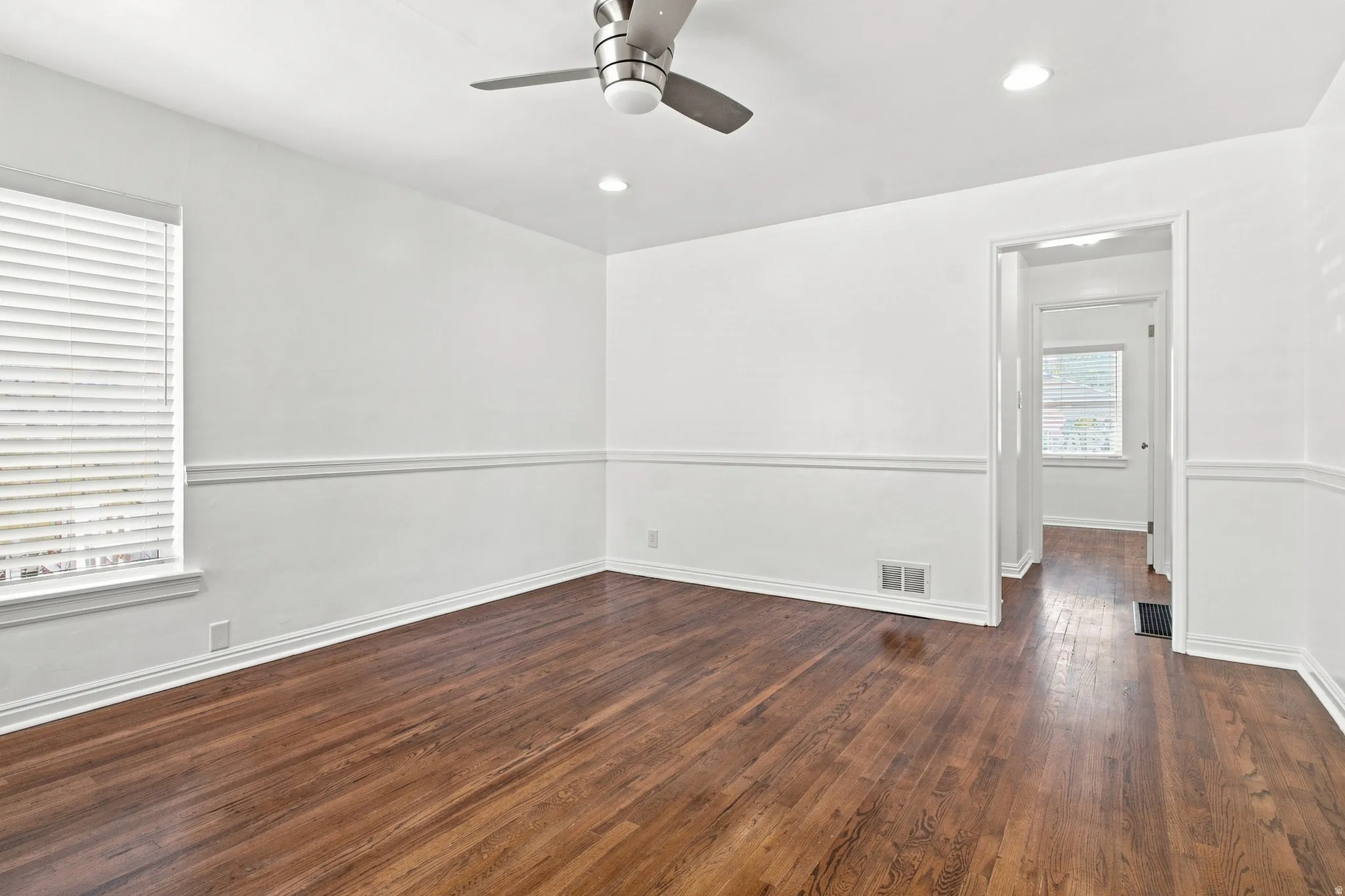 Hardwood flooring, recessed lighting, ceiling fan, chair rail molding, and window with blinds