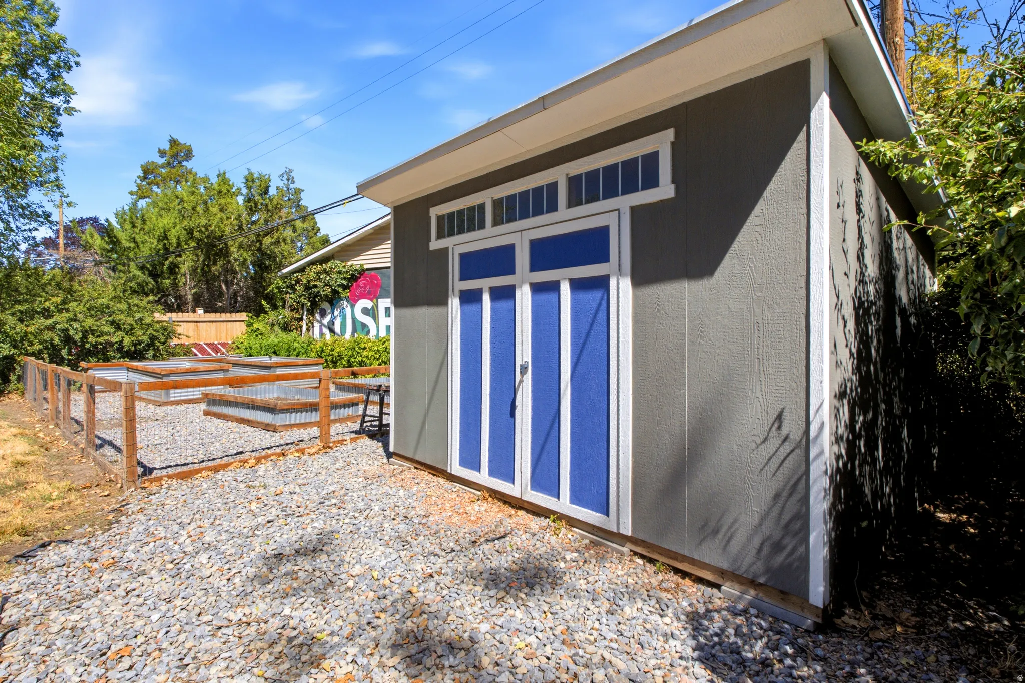 Freestanding storage shed with blue double doors and transom windows
