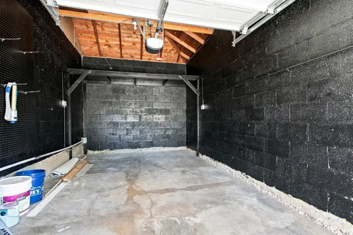 Exposed wood beam ceiling, concrete block walls, and concrete flooring