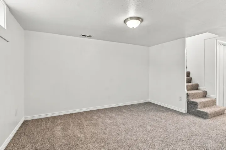 Recessed window, ceiling-mounted light fixture, carpeted flooring, and a carpeted staircase