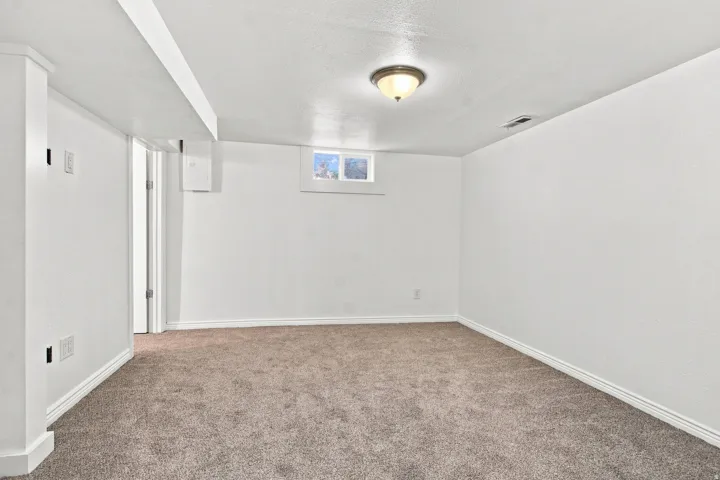 Neutral tone carpeting, white painted walls, and a semi-flush mount ceiling light