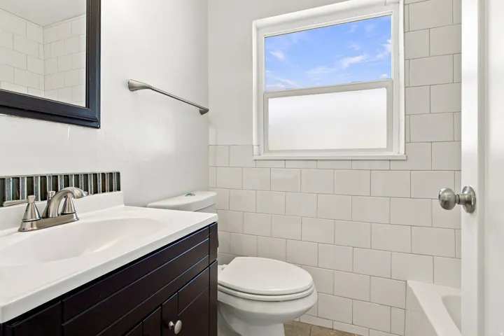 White subway tile walls with dark vanity, integrated sink, and brushed nickel fixtures