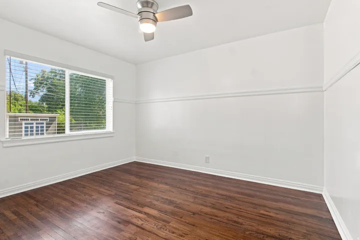 Hardwood flooring, white walls with decorative molding, and a ceiling fan with integrated lighting