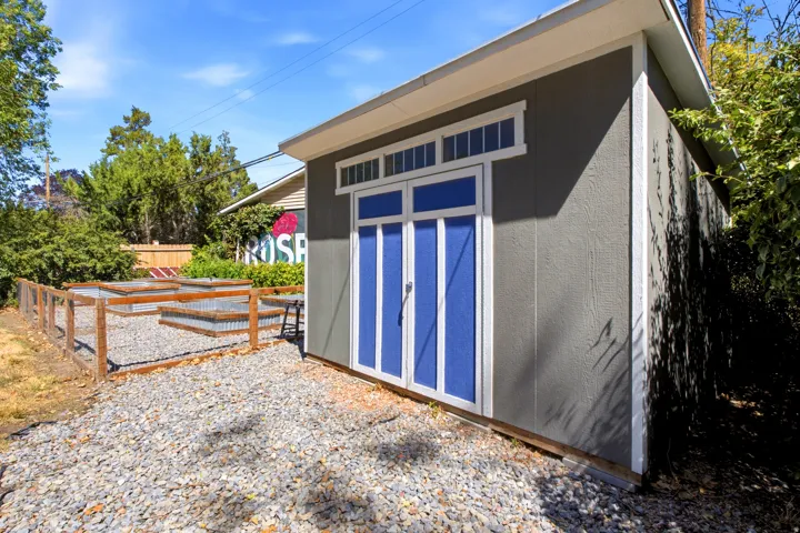 Freestanding storage shed with blue double doors and transom windows