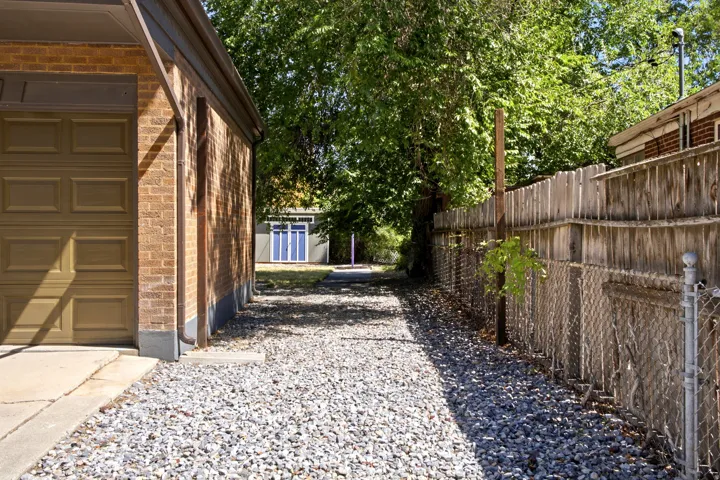 Brick exterior with a garage door, gravel RV parking, and wood fencing