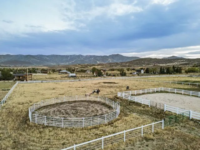 Expansive outdoor equestrian space featuring a round pen and an additional arena