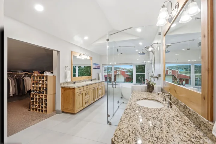 Dual vanity with granite countertops, light wood cabinetry, and vessel sinks