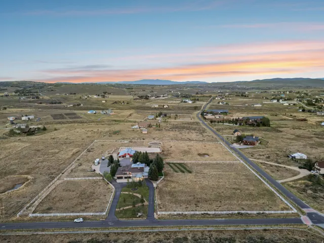 Expansive property featuring a paved driveway, a large main residence, and additional structures