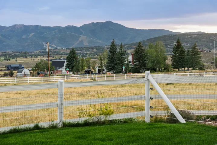 Expansive natural landscape featuring distant mountains and a white fence bordering a grassy area