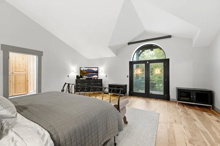 Vaulted ceilings, wood-finish flooring, and French doors with an arched transom