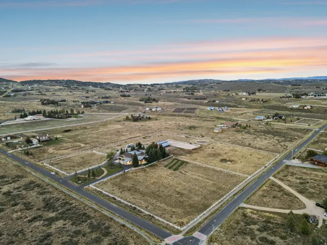 Expansive property featuring a residence, detached buildings, a fenced perimeter, and road frontage