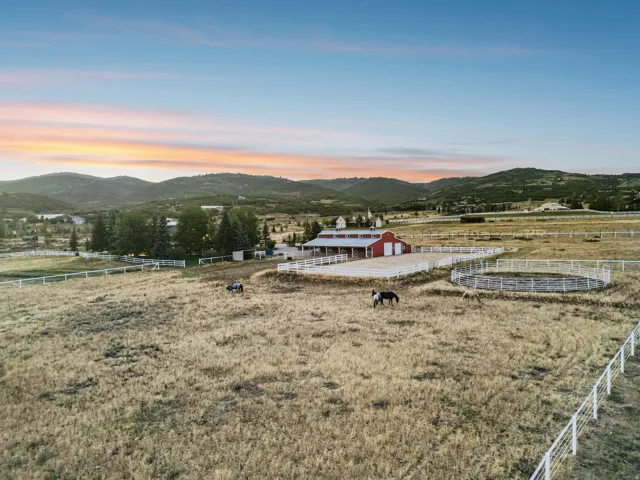 Expansive acreage featuring a red barn, white fencing, and a round pen