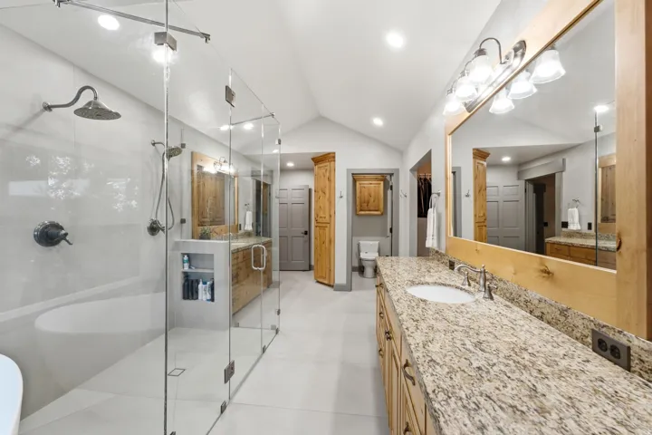 Dual vanity with stone-finish countertops, wood-finish cabinetry, and framed mirrors
