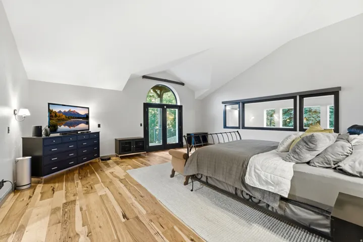 Vaulted ceilings, wood-finish flooring, and French doors with an arched transom