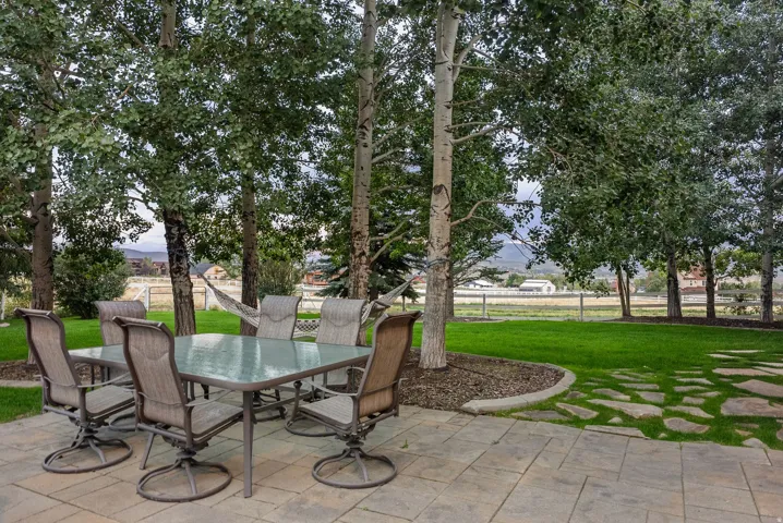 Paver patio with a stone path, manicured lawn, and mature trees