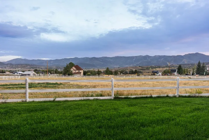 Manicured lawn with a white fence, expansive field, and distant mountains
