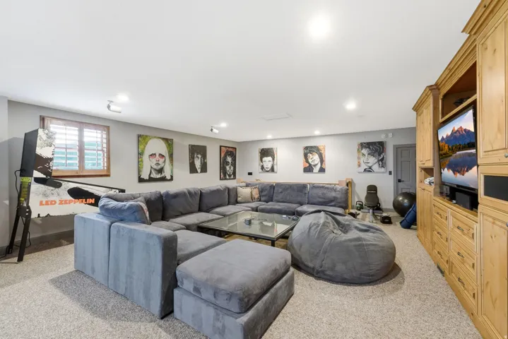Recessed lighting illuminates the space with light-colored carpet flooring