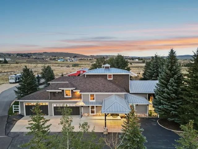 Exterior featuring a gray siding facade, stone accents, multiple garage doors, and a metal roof