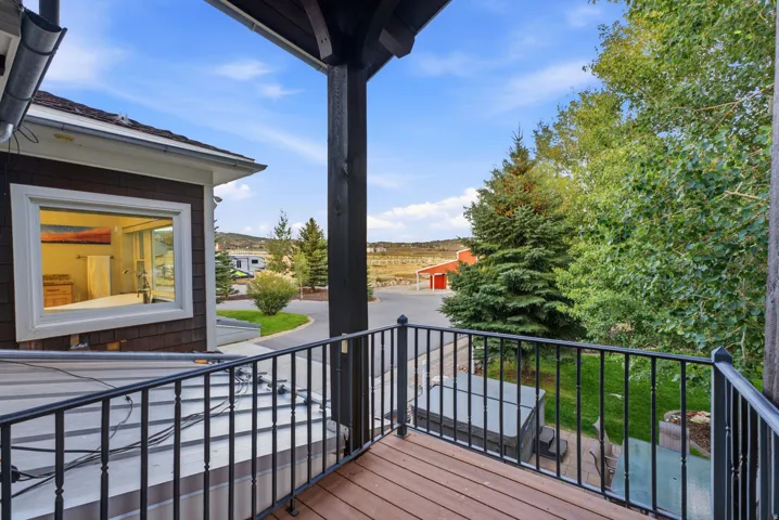 Balcony with wood-finish decking, wrought iron railing, and dark-stained support beams