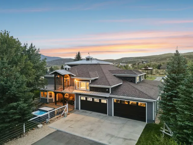 Contemporary residence featuring a multi-car garage, upper-level balcony, ground-level patio, and built-in spa